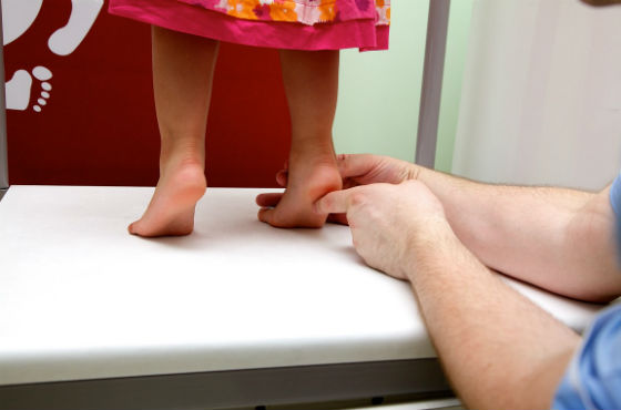 Осмотр врачом стопы ребенка для диагностики патологий