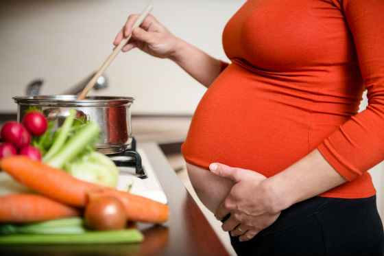 Беременная женщина готовит пищу