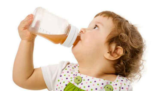 Ребенок пьет сок из бутылочки с соской